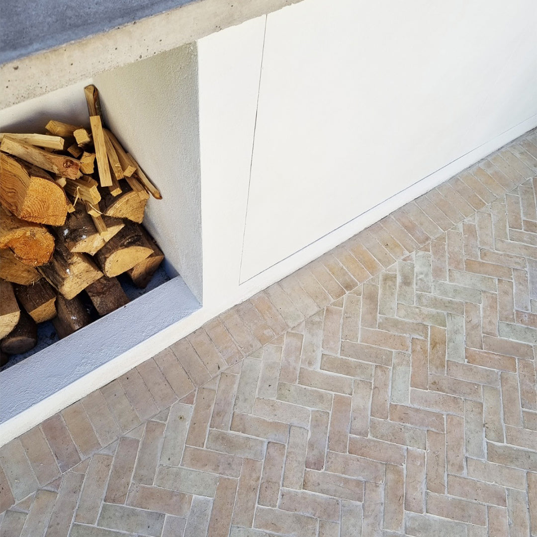 Light brick-pattern bathroom flooring with recessed firewood storage, combining rustic decor and modern interior design elements.