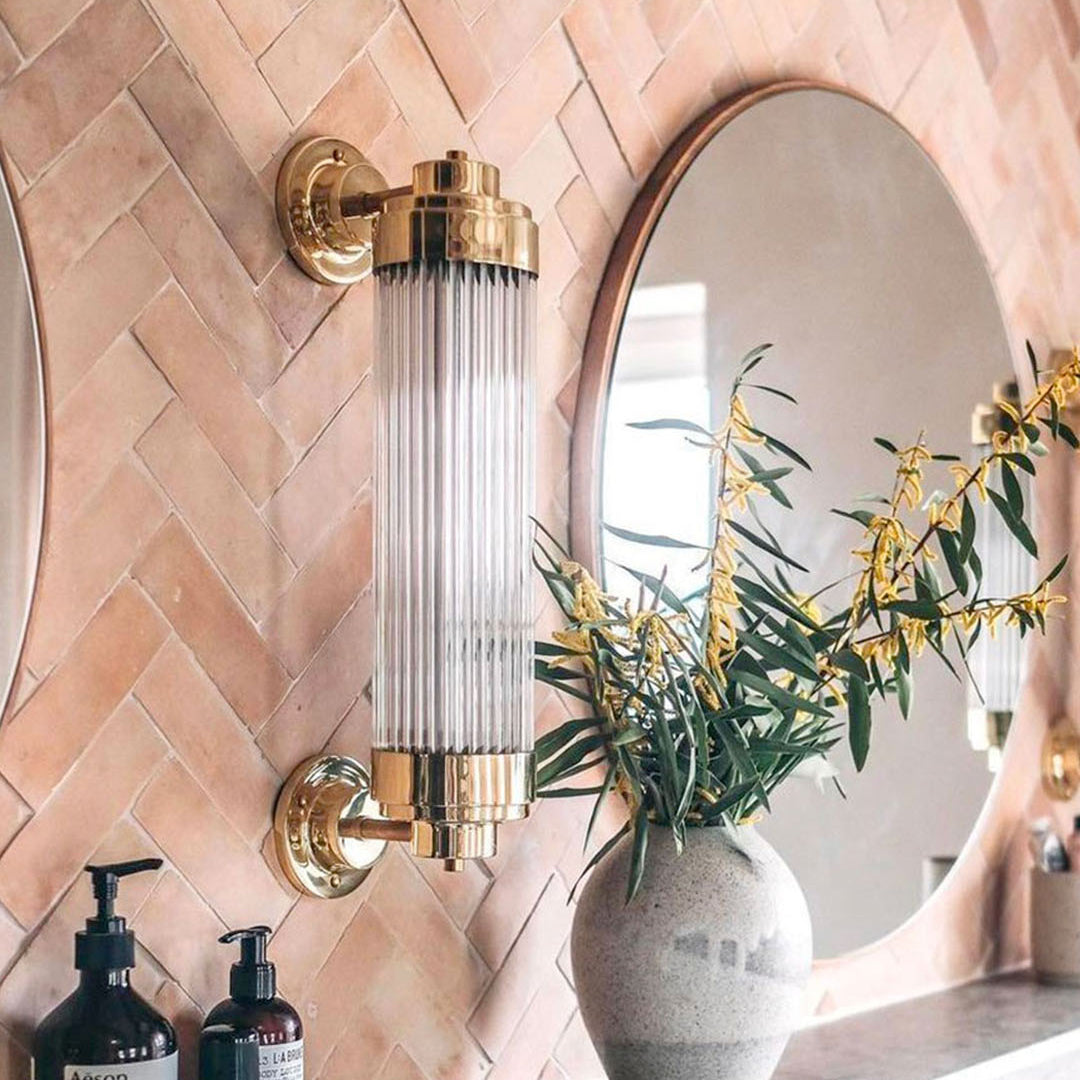 Decorative wall sconce with a mirror and plant in the background
