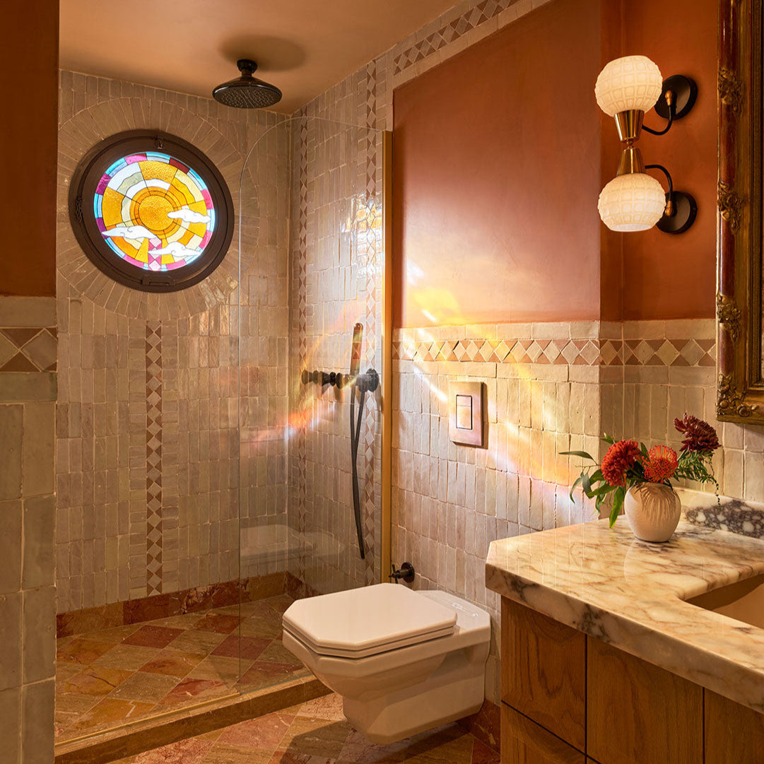 Bathroom with tiled walls, a stained glass window, and a vanity with flowers.