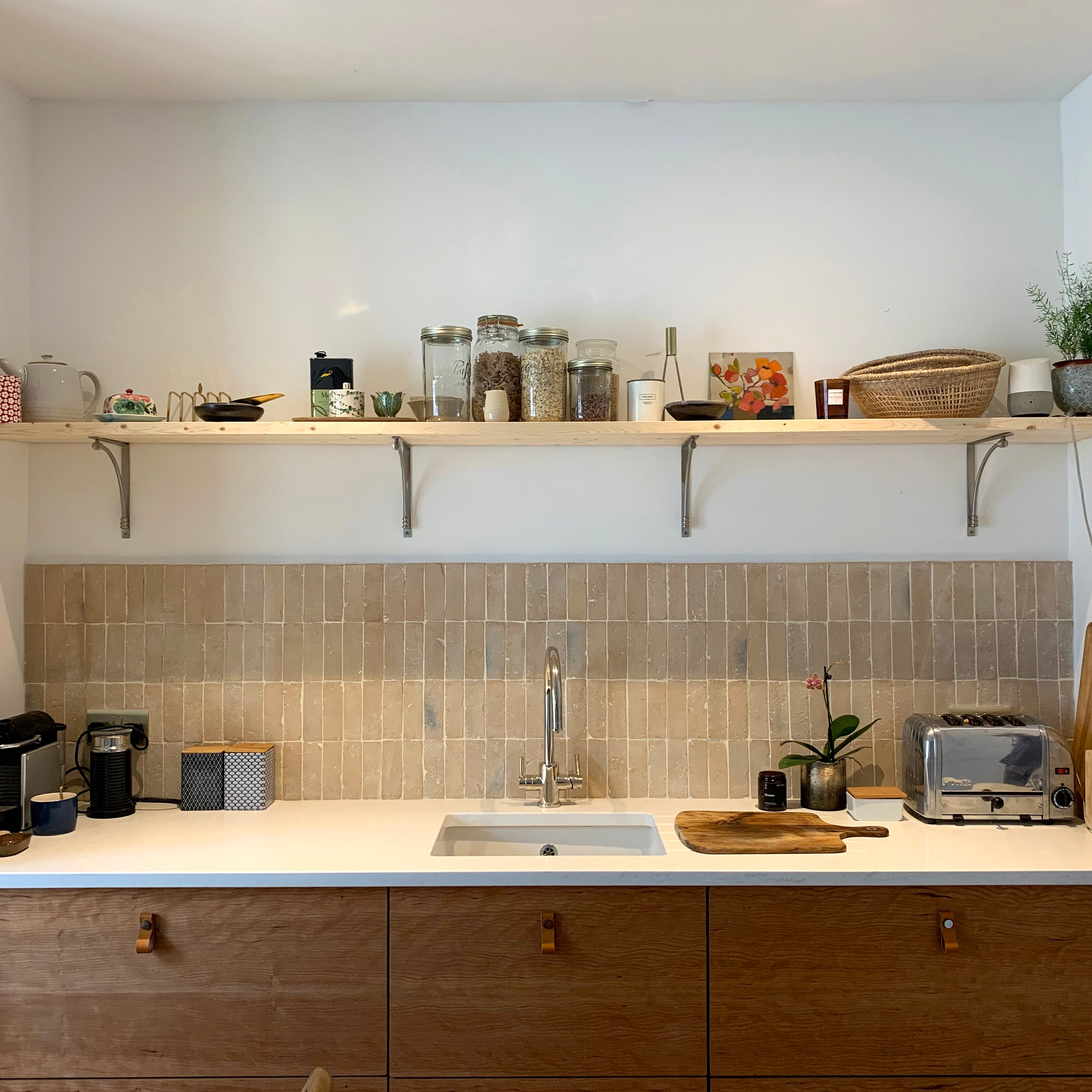 Modern kitchen with wooden cabinets, white countertop, and tiled backsplash.