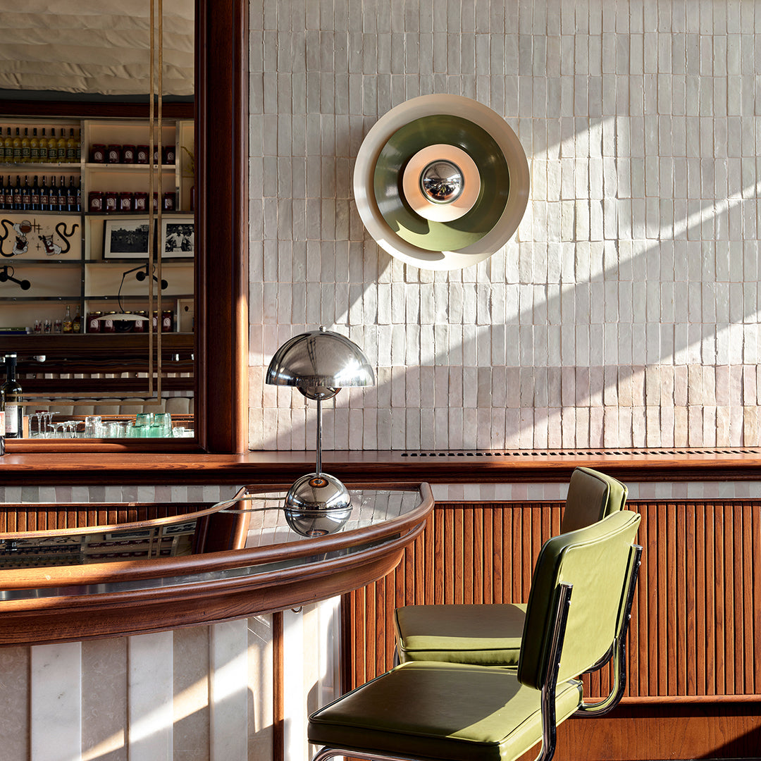 Modern interior with a bar counter, green chairs, and wall-mounted lamp.
