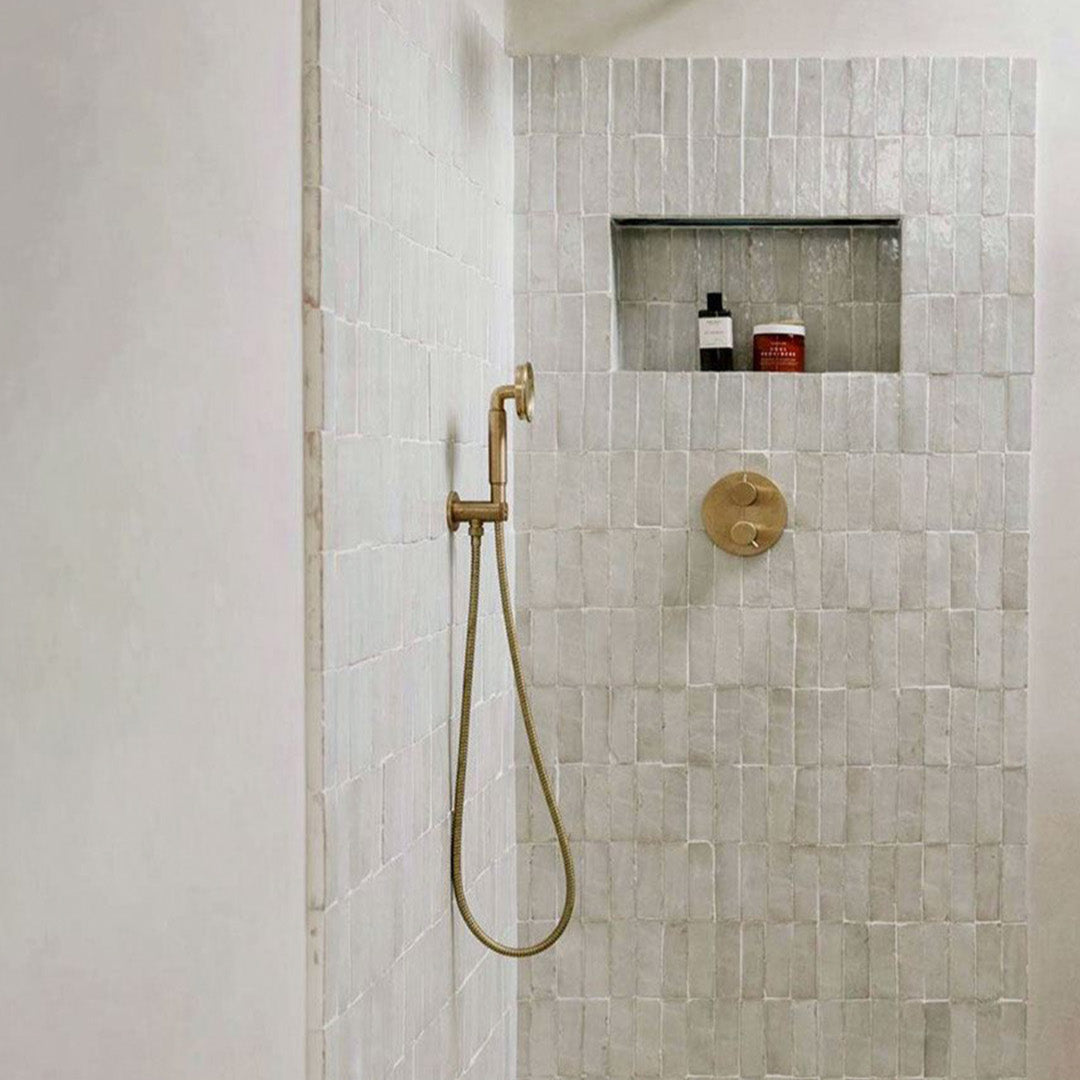 Modern shower setup with tiled walls and gold fixtures