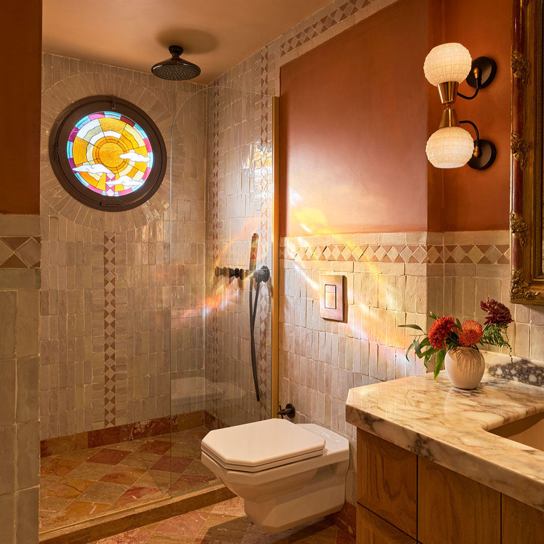 Bathroom with tiled walls, a stained glass window, and a vanity with flowers.