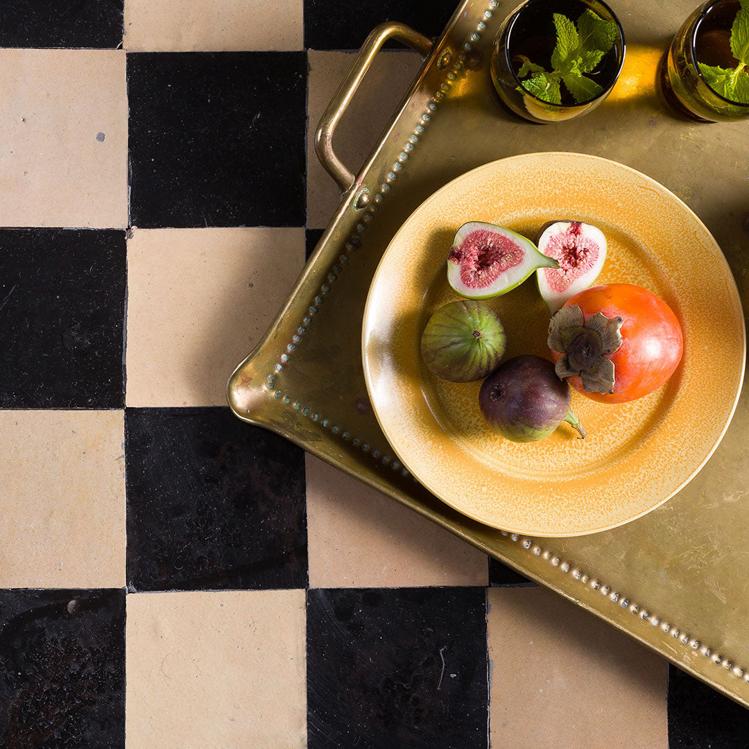 Fruits on a gold plate with a checkered floor background
