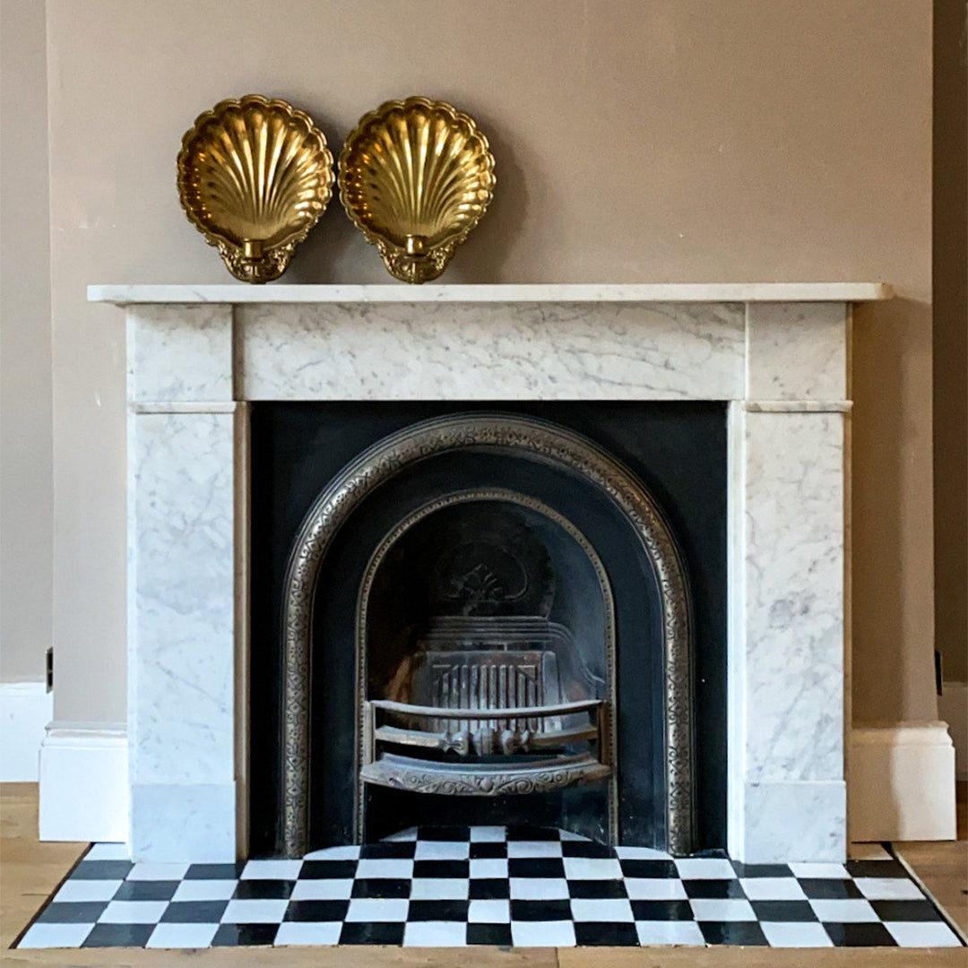 Marble fireplace with gold shell decorations and a black and white checkered hearth rug.
