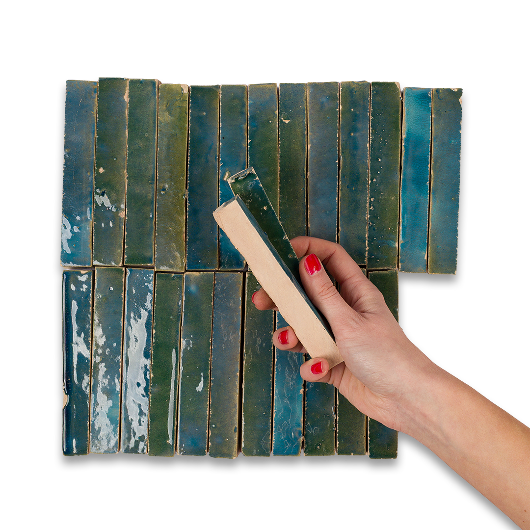 Hand holding a book with a green cover over a stack of books on a white background
