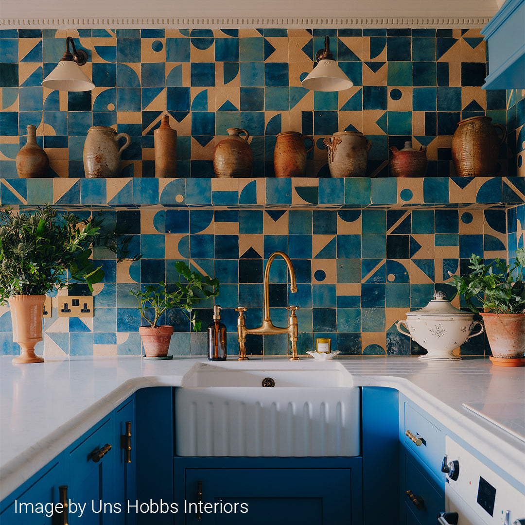 Modern kitchen with geometric tile backsplash, white sink, and blue cabinets.