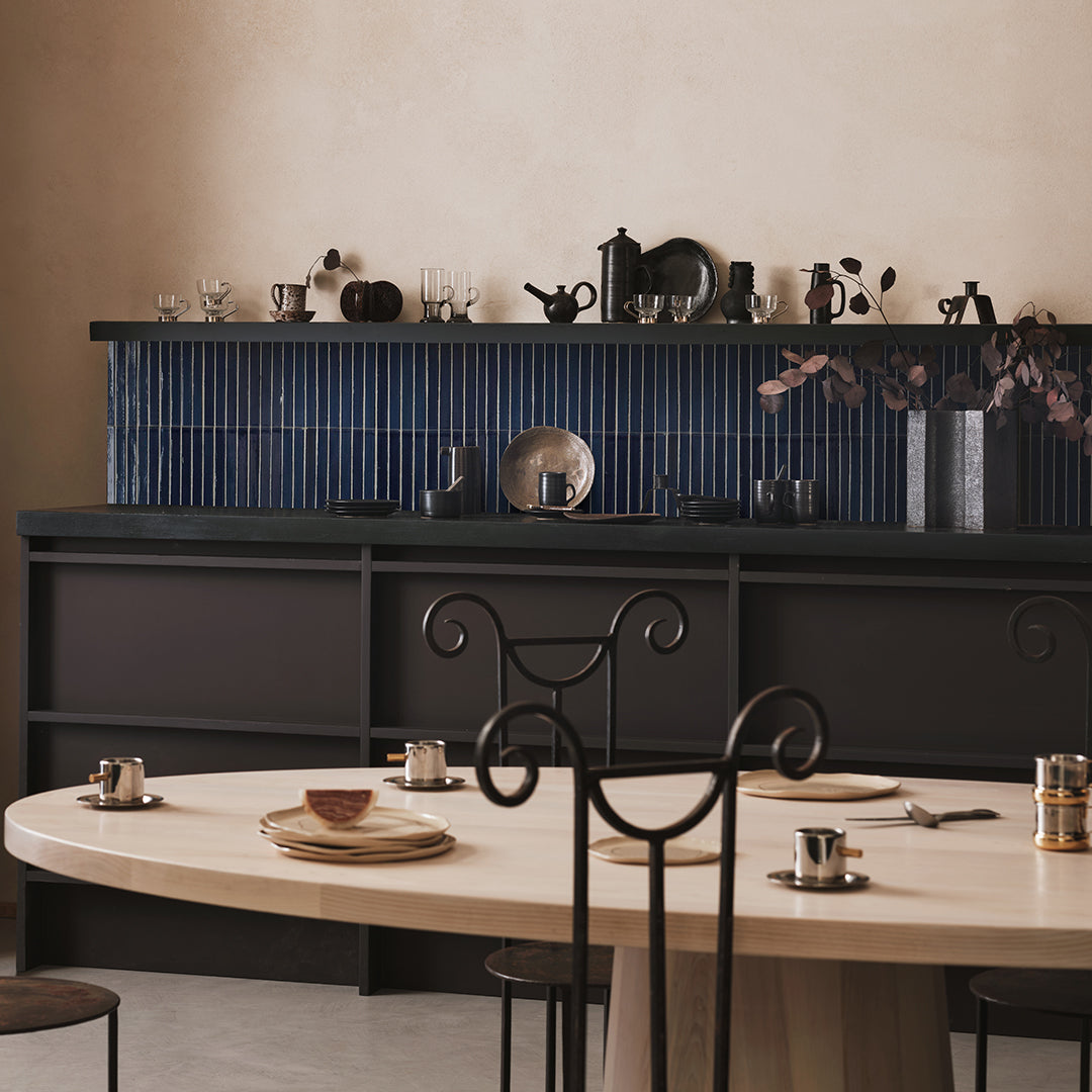 Dining area with a table set for four, black chairs, and a dark wall with decorative elements.