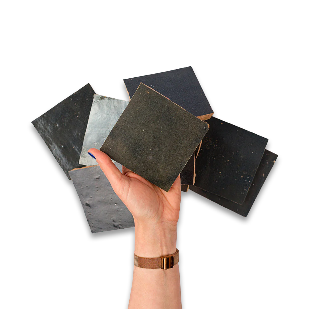 Hand holding a collection of dark-colored square samples against a white background