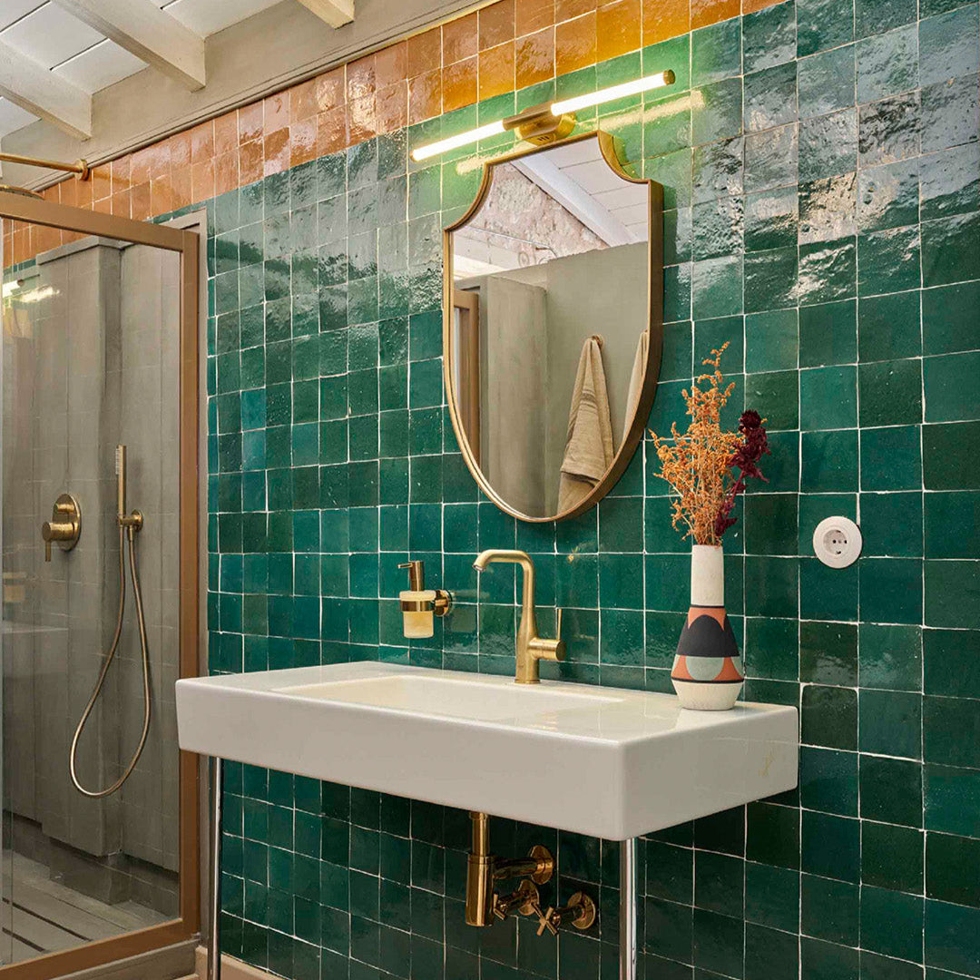 Bathroom with green tiles, white sink, and gold fixtures