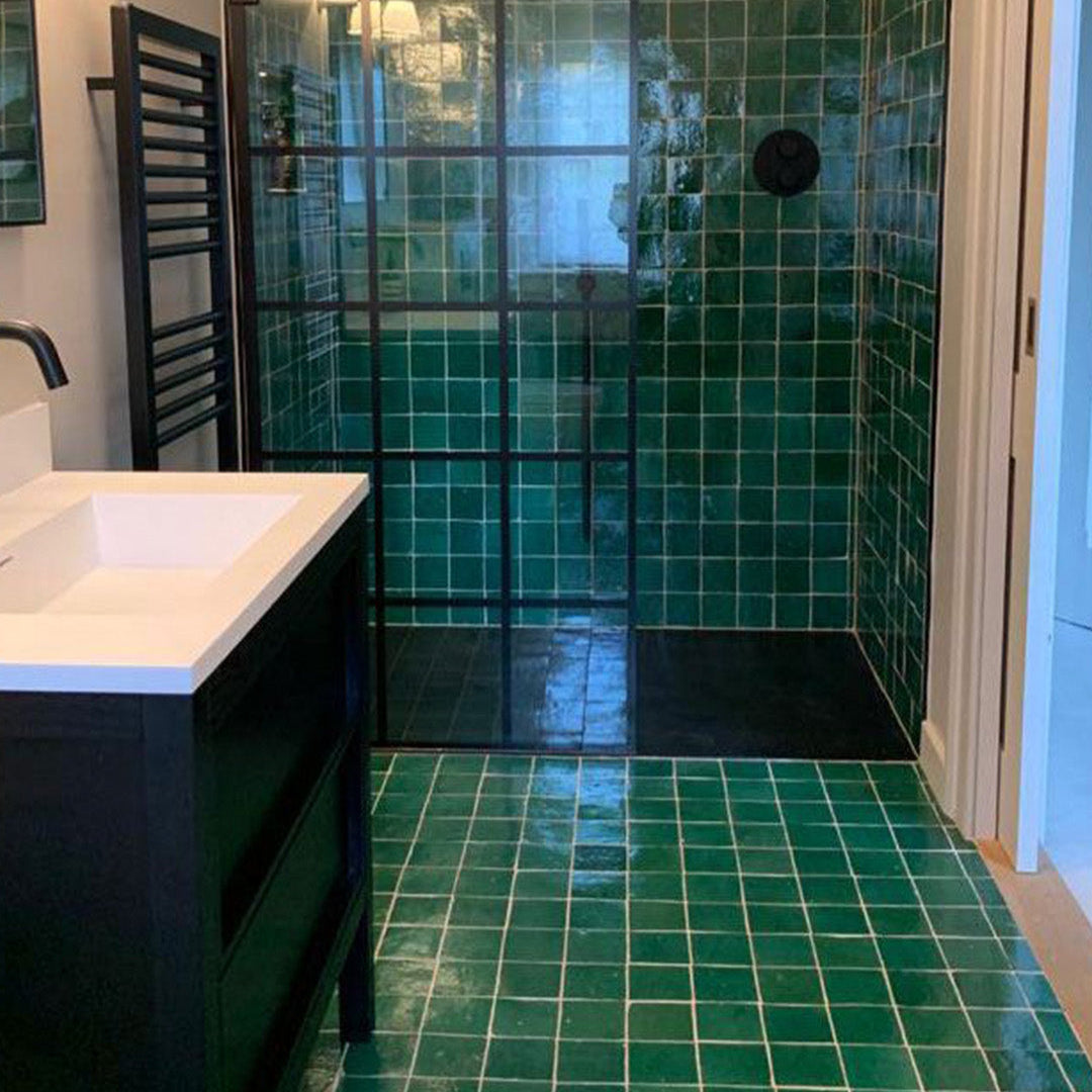 Bathroom with green tiled floor and walls, featuring a shower area.