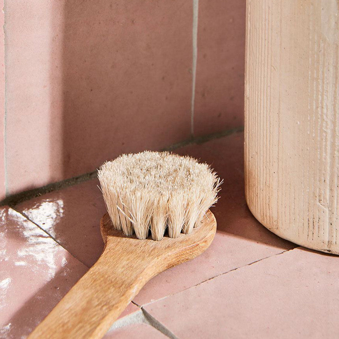 Wooden brush with bristles on a pink tiled floor