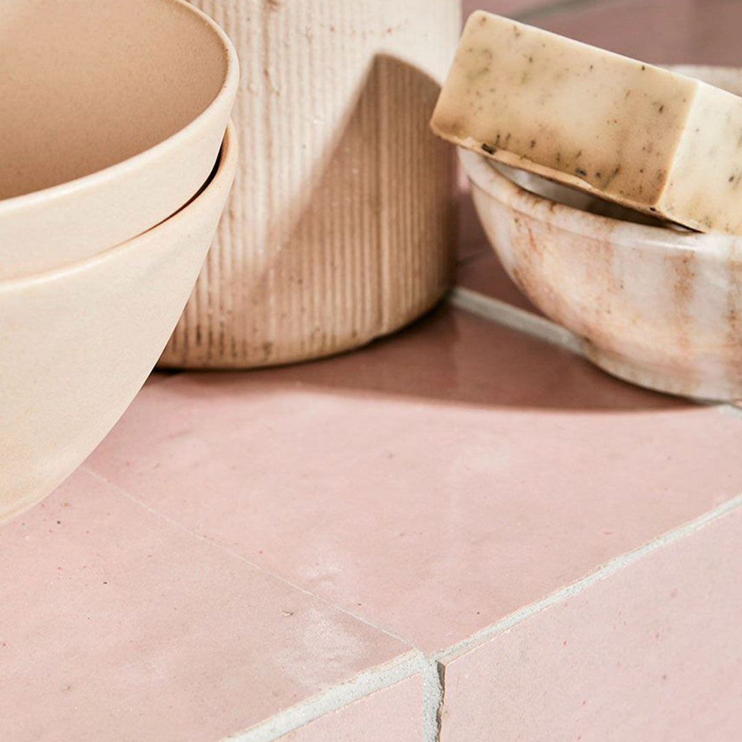 Bowl with soap on a pink tiled surface