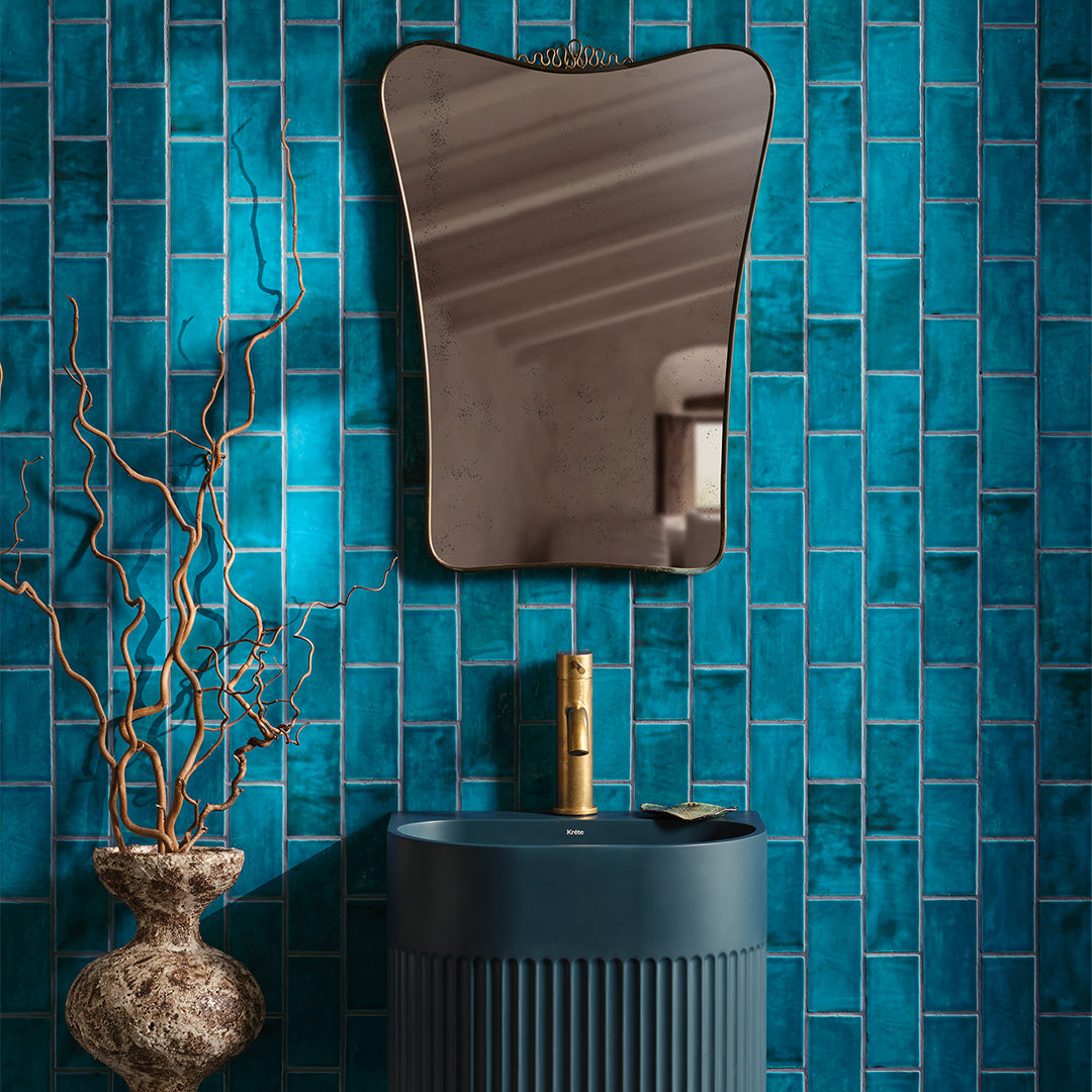 Bathroom with blue tiled wall, black sink, and decorative mirror.