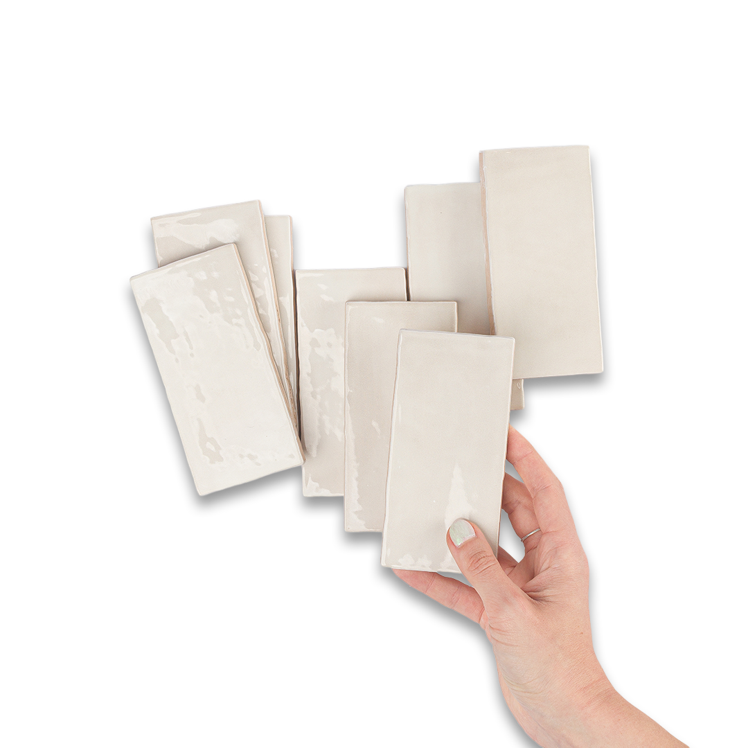 Hand holding a stack of white ceramic tiles on a white background