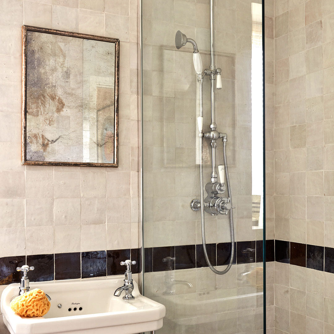 Bathroom with tiled walls, a sink, and a shower area.