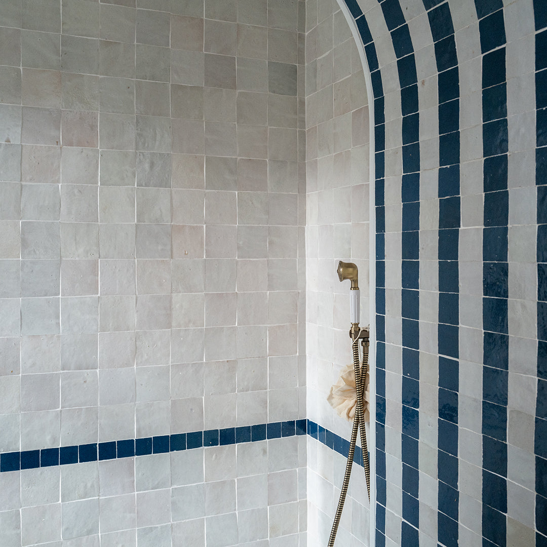 Bathroom corner with tiled walls and a shower head.
