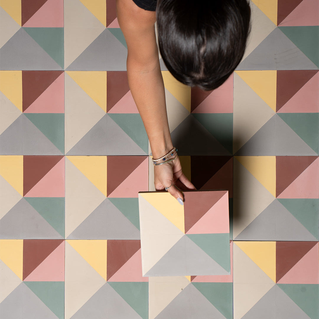 Cement tile featuring a geometric pinwheel pattern with pastel grey, yellow, green, pink, and terracotta triangles, matte finish, ideal for modern, mid-century, or eclectic interior flooring and wall décor applications.