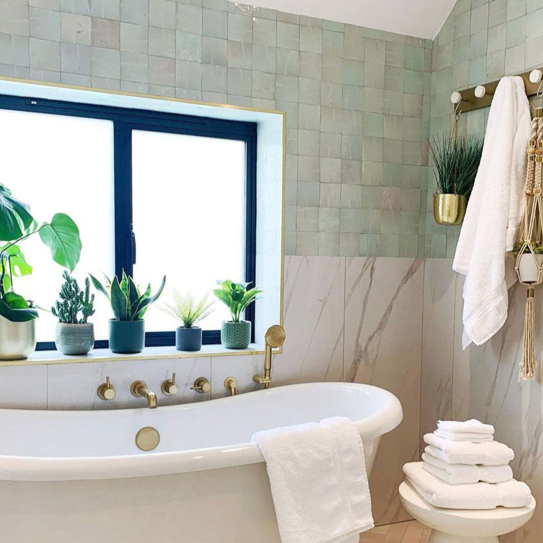Bathroom with a freestanding bathtub, towels, and decorative plants.