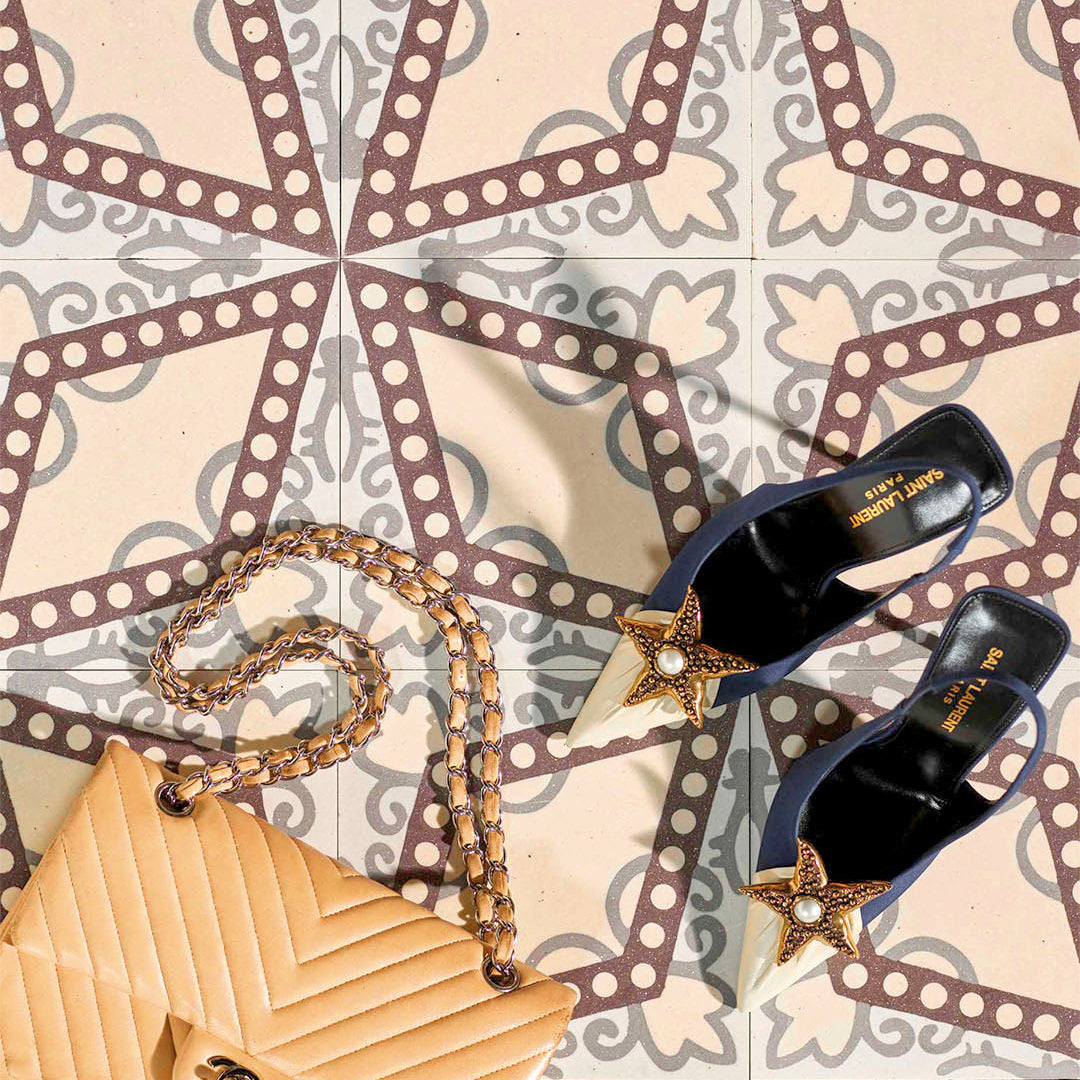 Beige handbag and black high heels with star details on a patterned surface