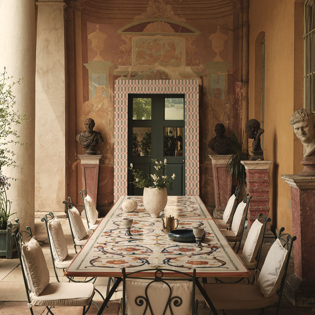 Dining room with classical decor, including statues and a patterned tablecloth.