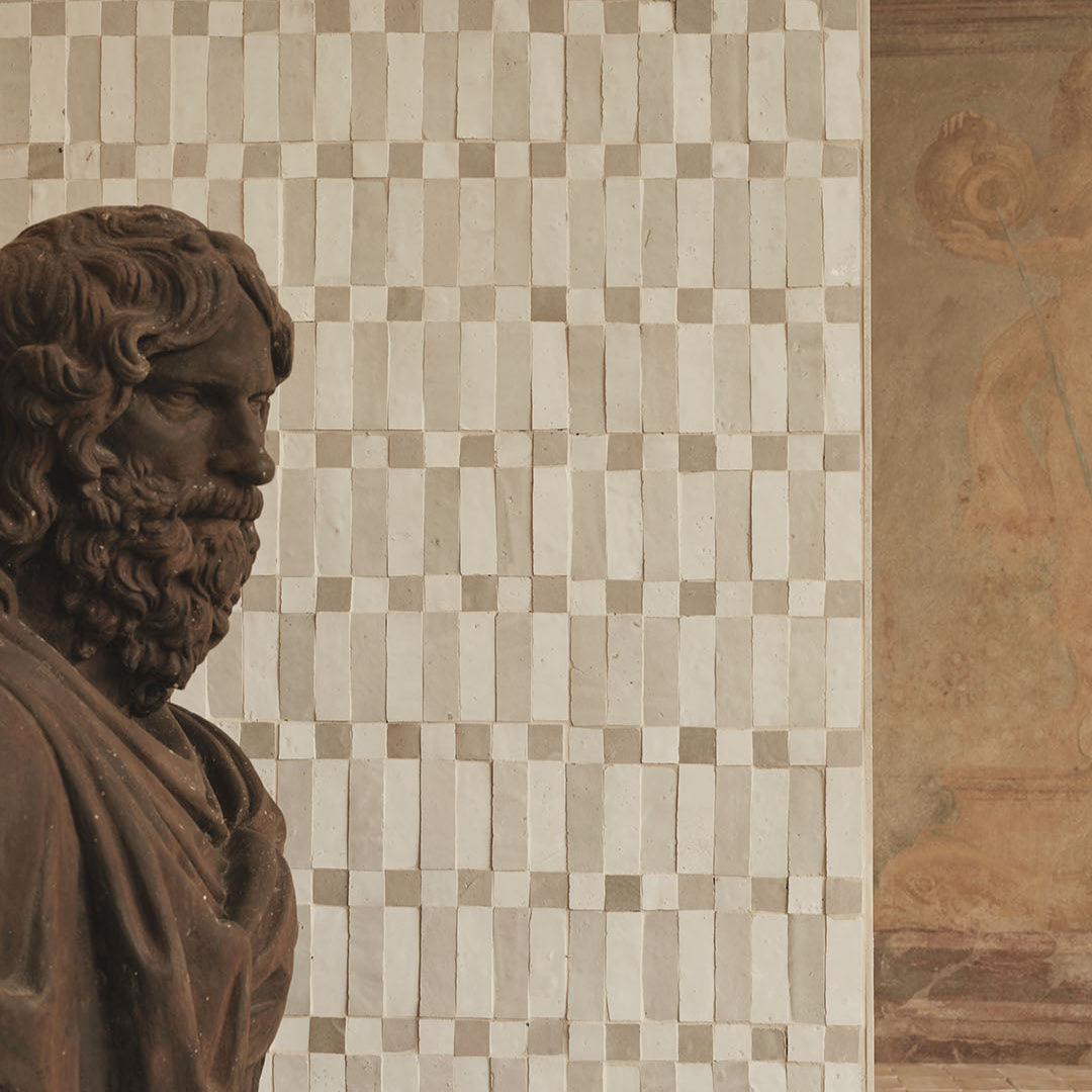 Bust of a classical figure in front of a mosaic wall