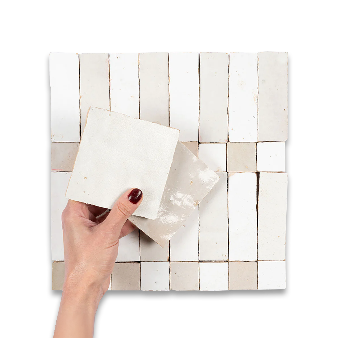 Hand holding a white rectangular object against a woven tile background