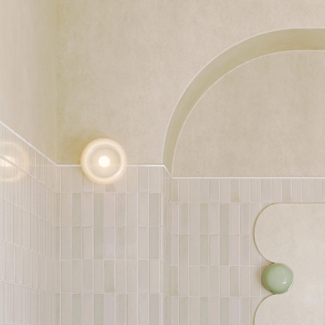 Shower enclosure with curved glass door and tiled walls.