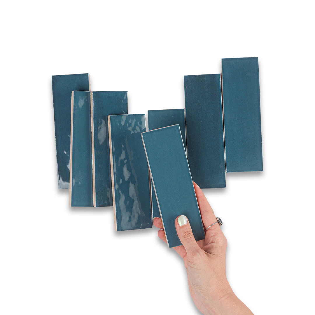 Hand holding a blue tile sample with multiple other tiles in the background on a white background