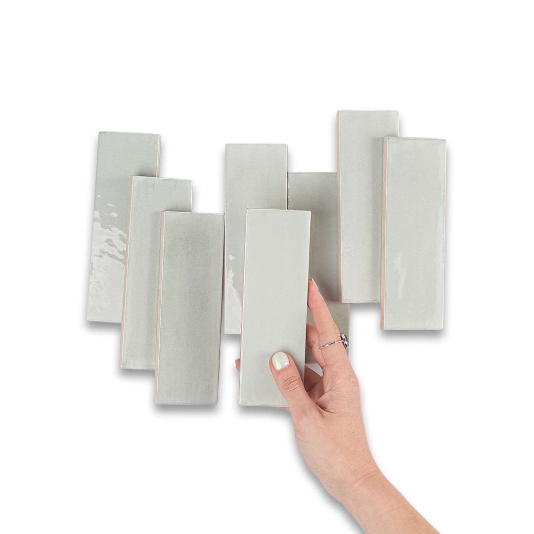 Hand holding a set of gray ceramic tiles against a white background