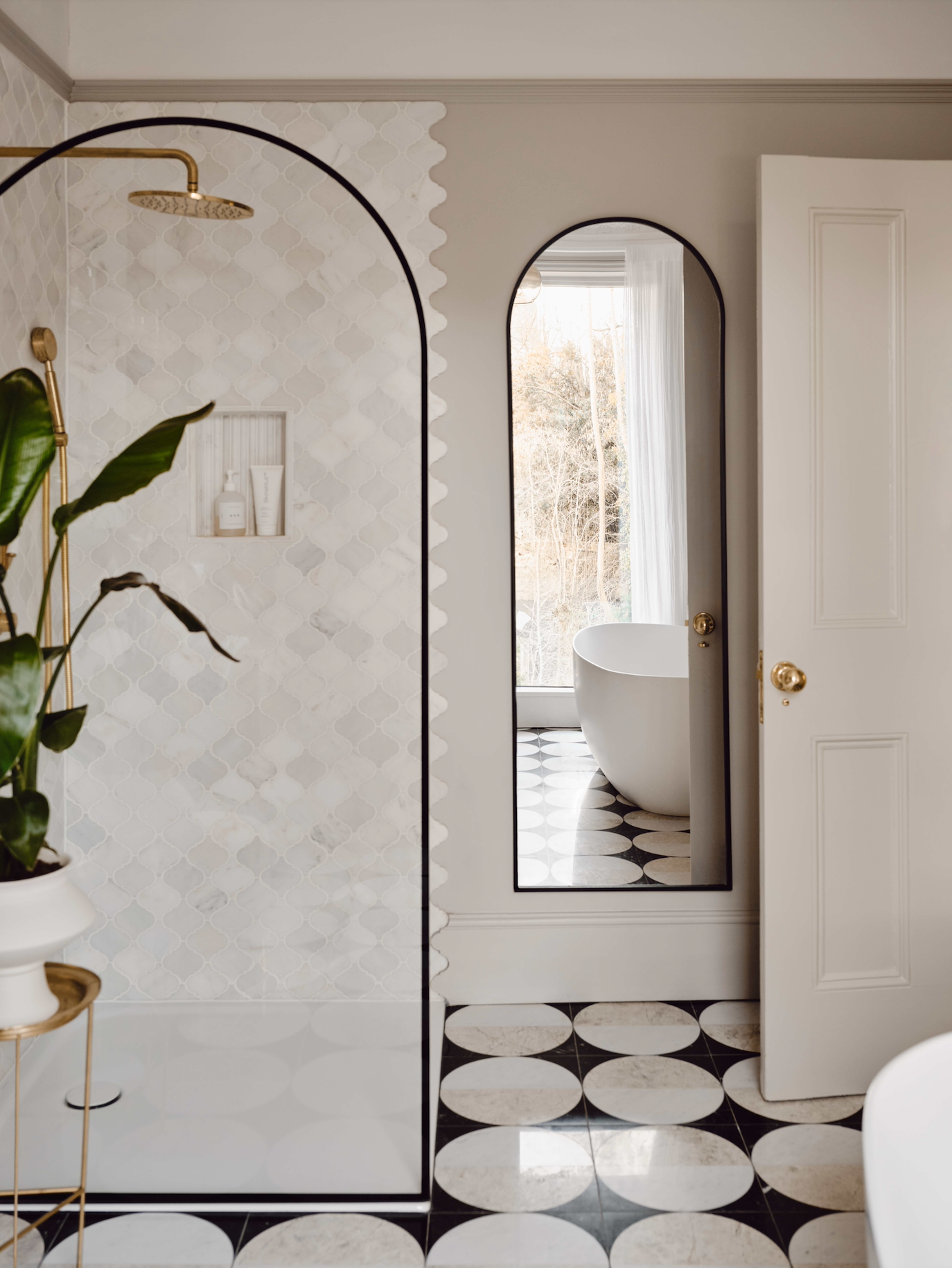 Bathroom with marble tiles, a freestanding bathtub, and a large mirror.