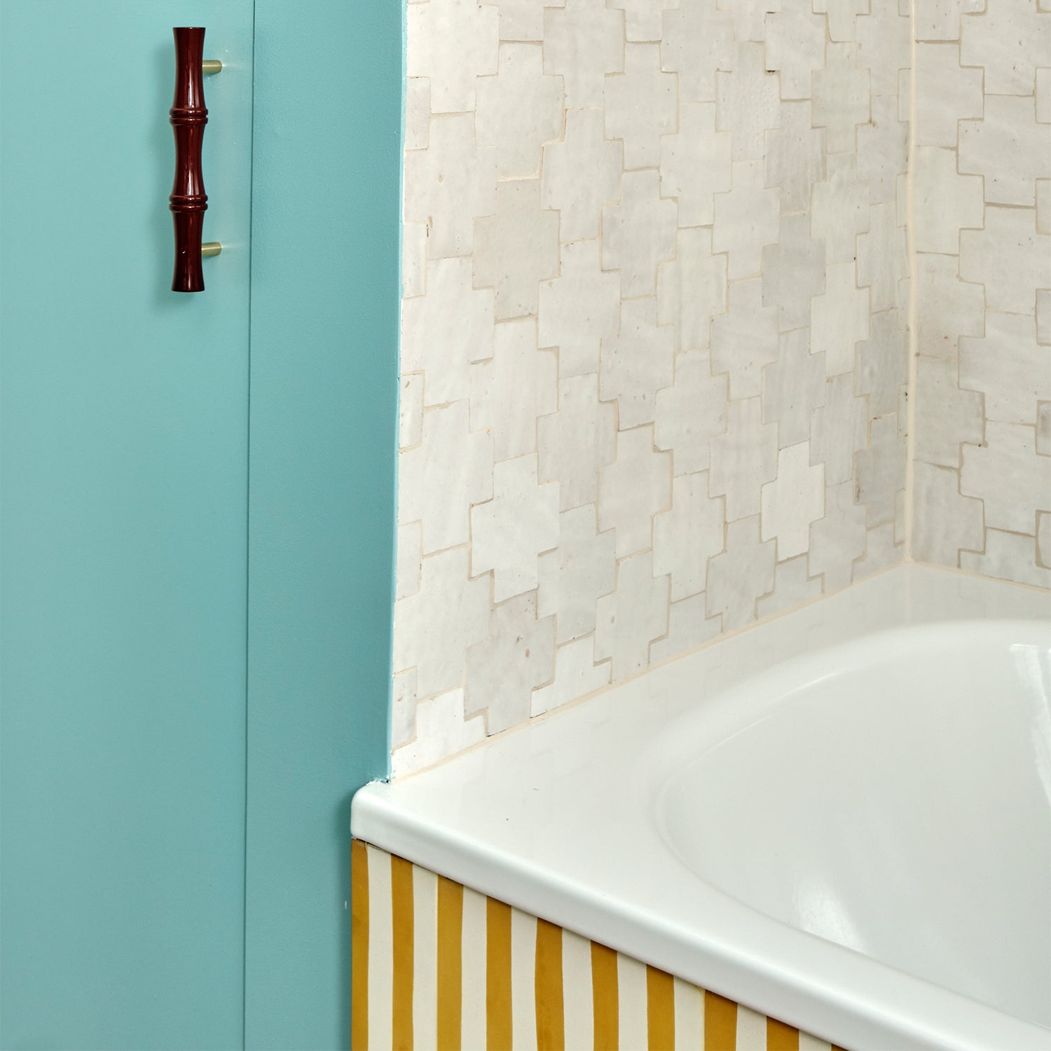 Bathroom corner with a bathtub, tiled wall, and wooden handle.