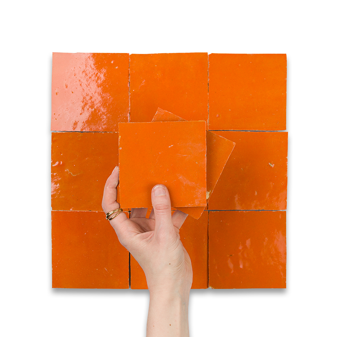Hand holding an orange square tile against a grid of orange tiles on a white background