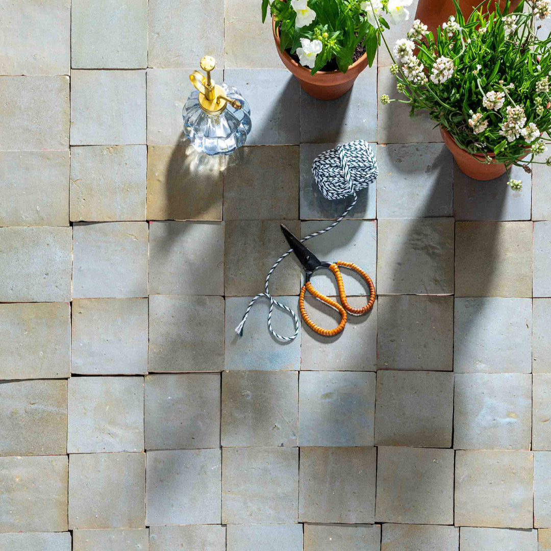 Decorative items including a bottle, scissors, and potted plants on a tiled surface.
