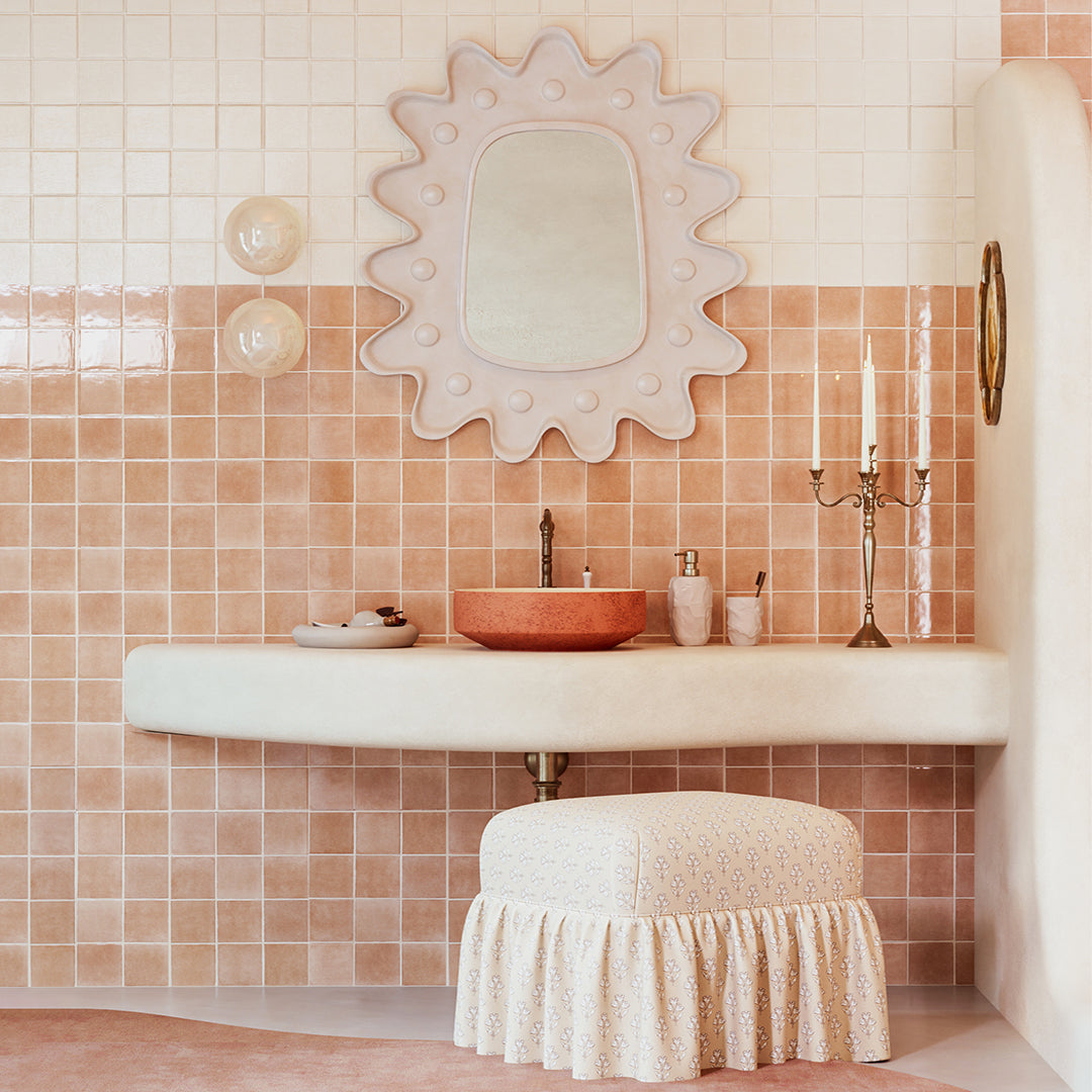 Bathroom with tiled walls, a sink, and decorative mirror.