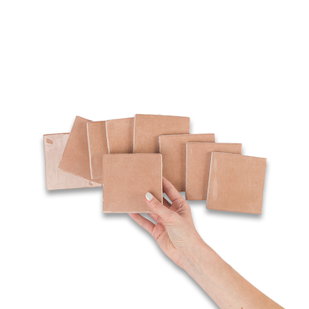 Set of square wooden coasters with a hand reaching to pick one up on a white background