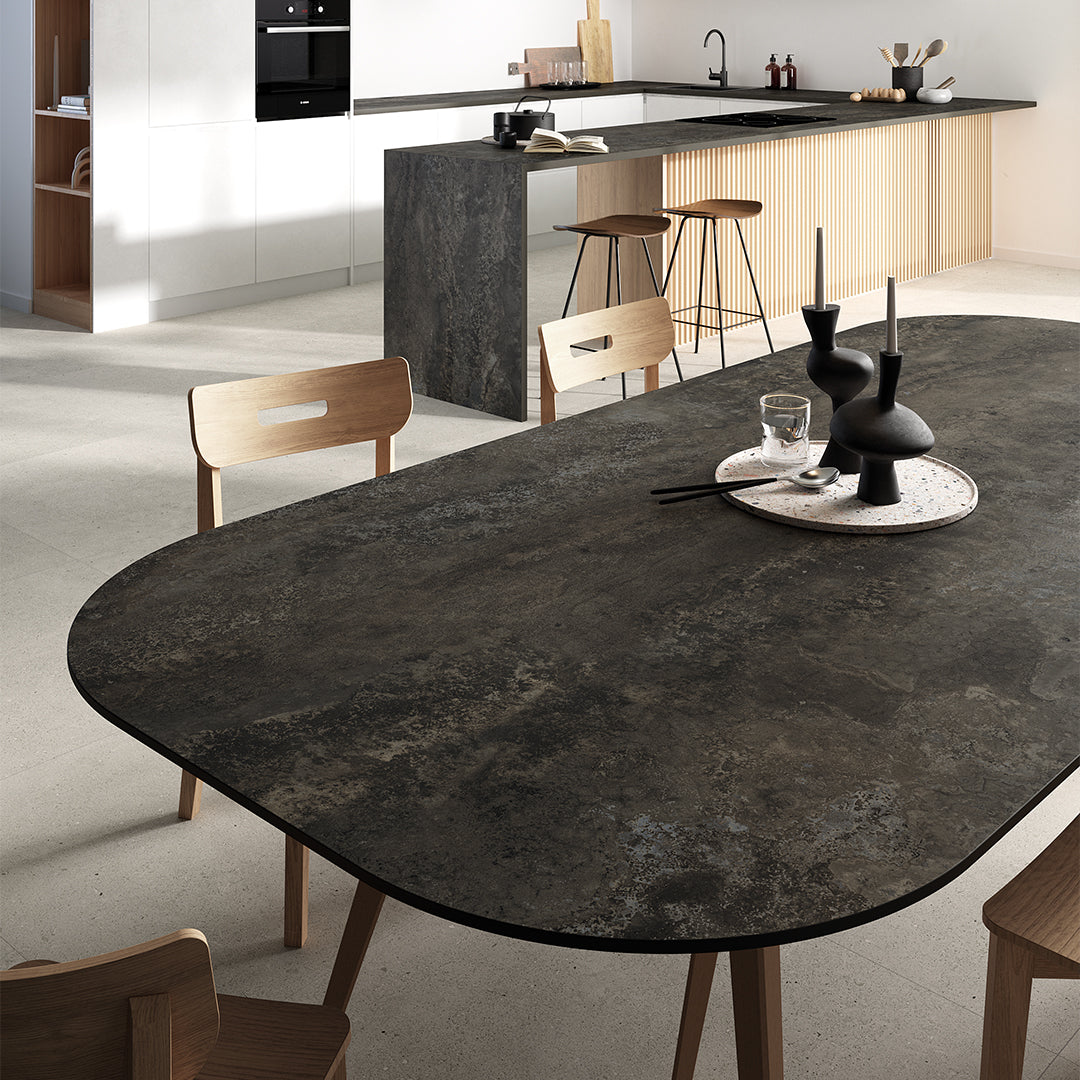 Round dark stone dining table in a modern kitchen setting with wooden chairs.