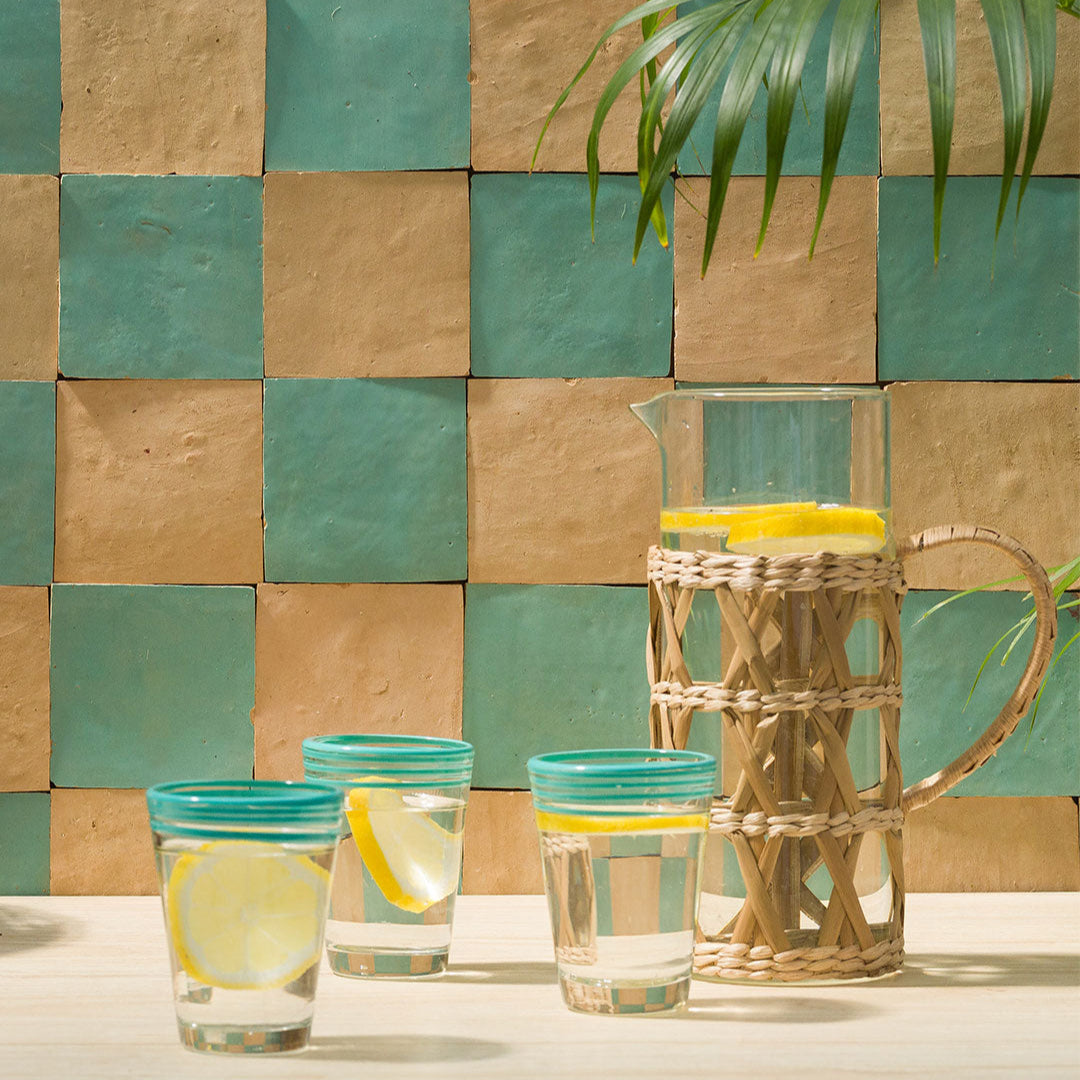 Glassware with lemon slices on a checkered tile wall background