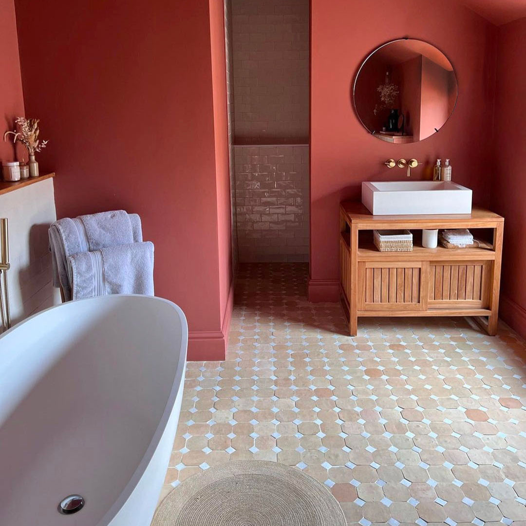 Bathroom with red walls, wooden vanity, and freestanding bathtub.
