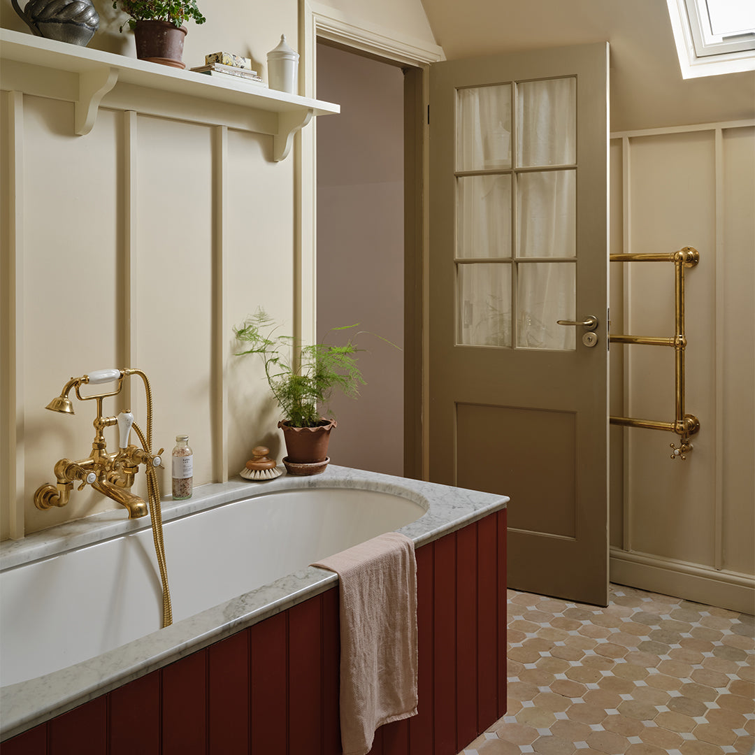 Bathroom with a bathtub, gold fixtures, and a door with glass panels.
