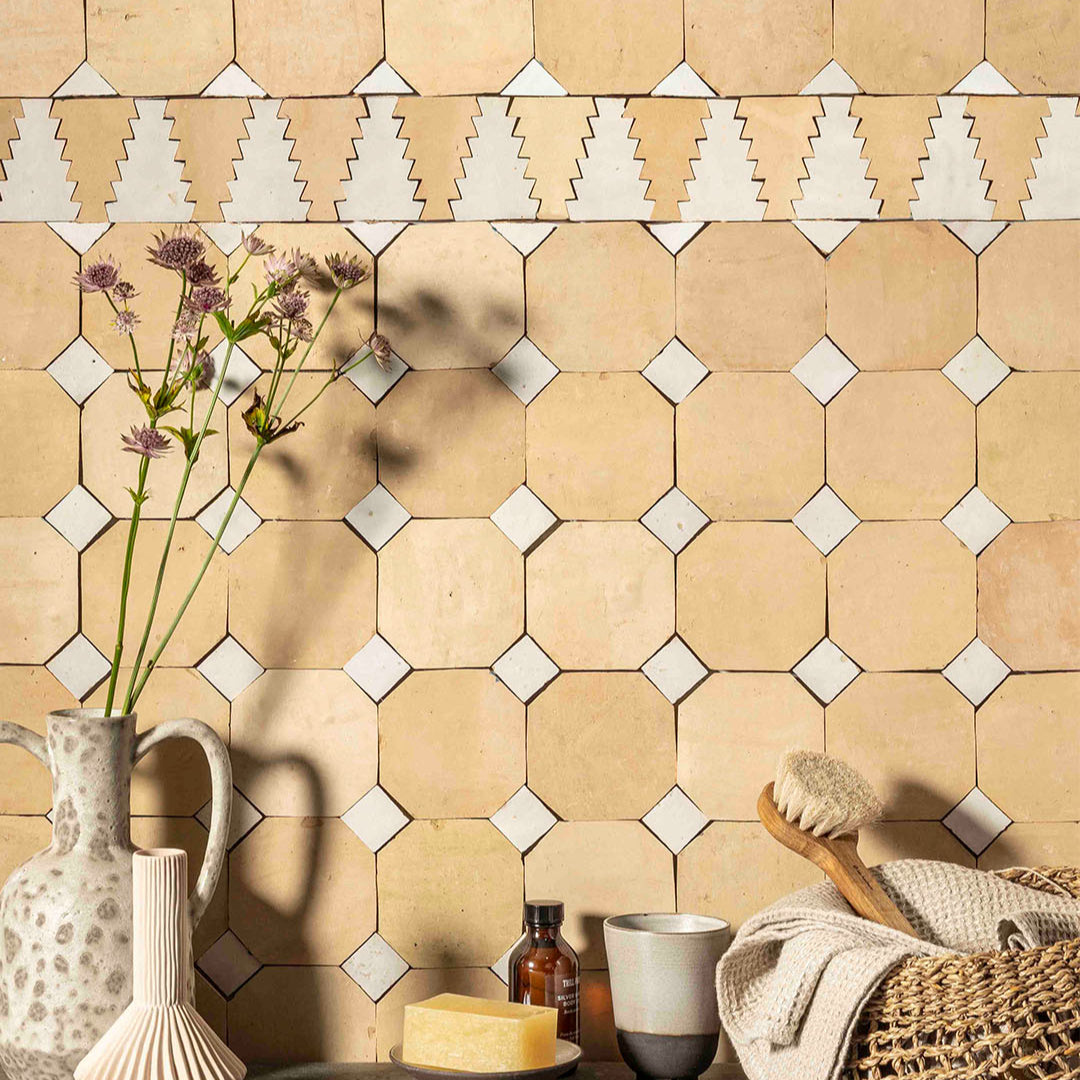 Beige hexagonal tiles with white accents on a wall, with decorative items like a vase and soap.
