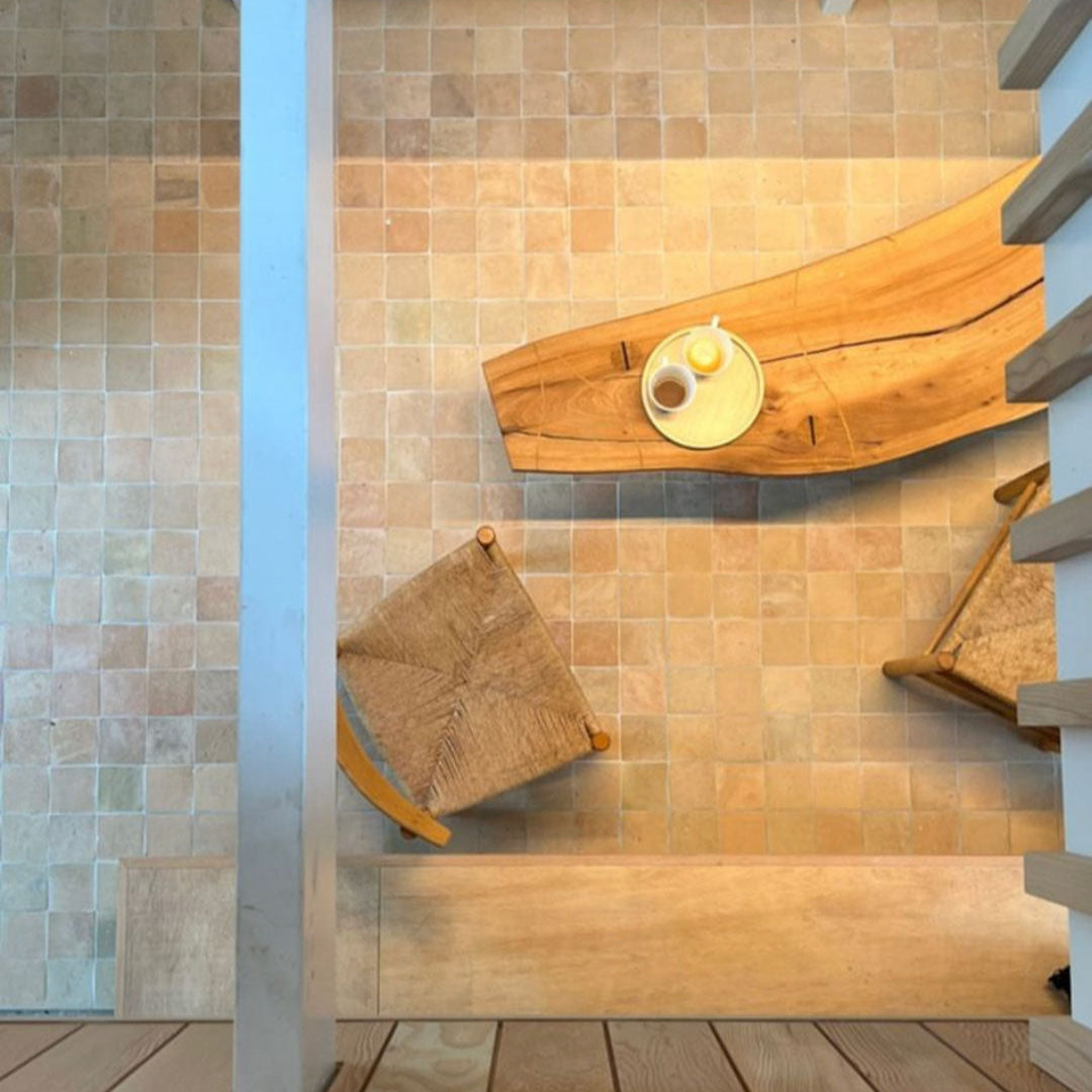 Wooden bench and stools against a tiled wall in a modern interior setting.