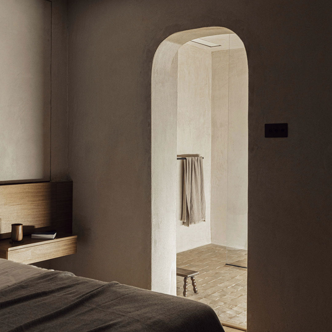 Bedroom with an archway leading to a bathroom, featuring neutral tones.