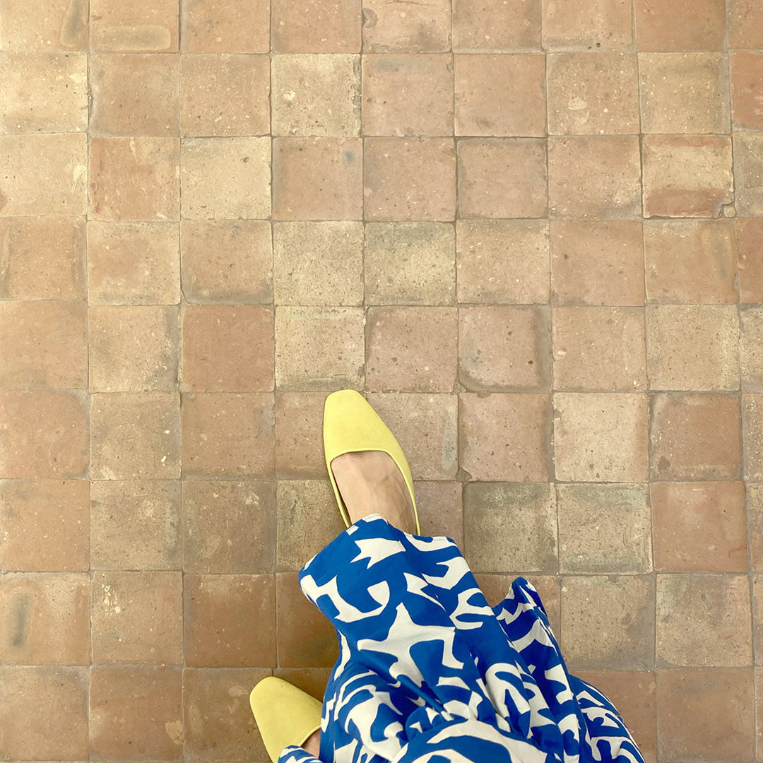 Yellow shoes with a blue and white patterned towel on a tiled floor