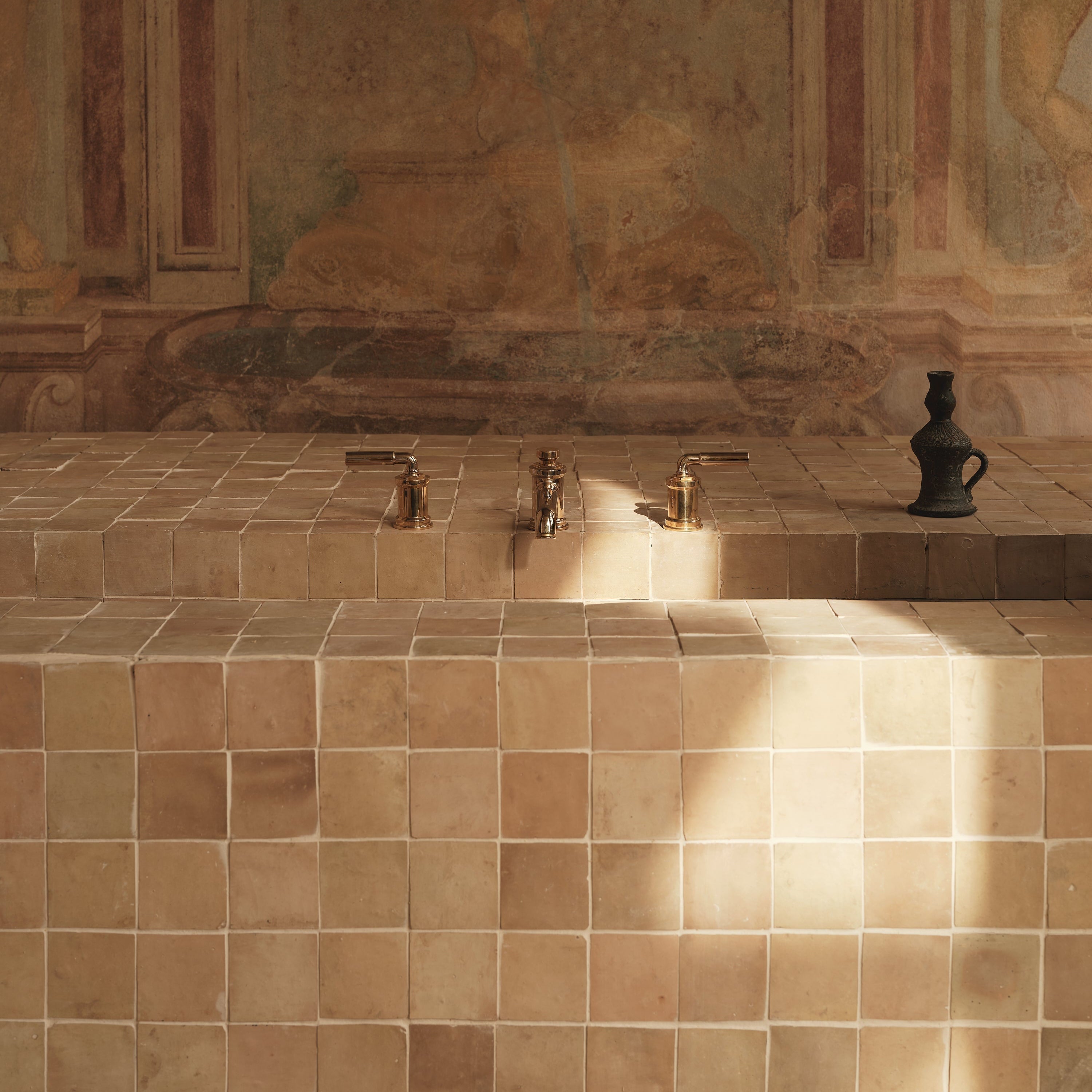 Tiled wall with classical fresco in a room with sunlight casting shadows